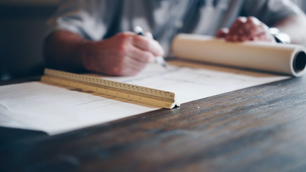 person writing on a blueprint