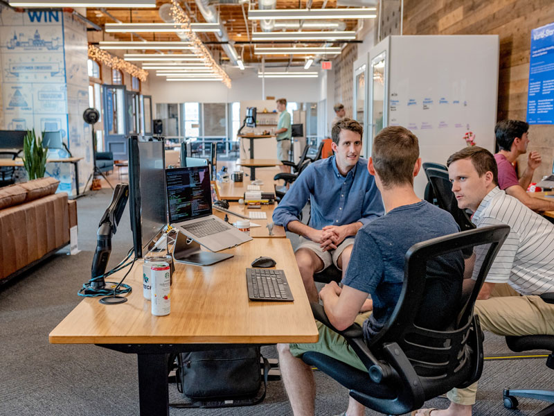 three men sitting at a computer