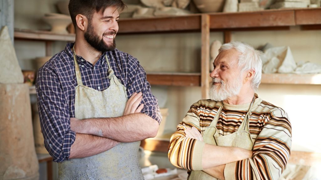 Transferring wealth between generations. A son/father or grandson/grandfather stare at eachother in their family place of business.